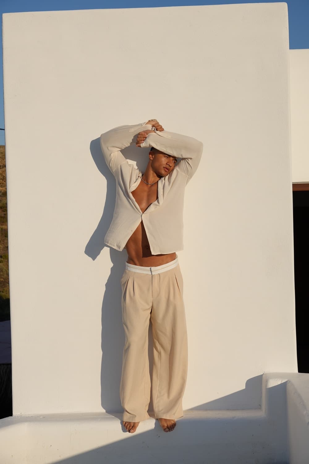 Nathan Nuyts in a light studio editorial outfit against a cream wall